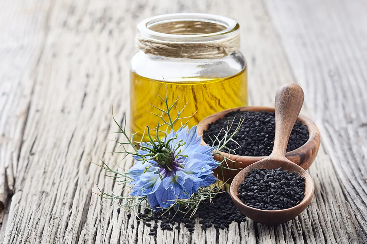 মধুর জাদুকরী কিছু গুণ 9 black cumin oil with flower nigella sativa wooden table