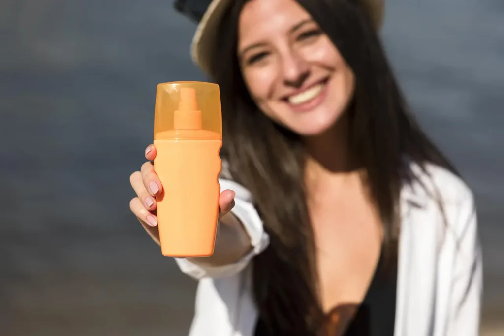 তপ্ত রোদে ত্বকের সুরক্ষা 6 smiley woman holding bottle sunscreen beach 1